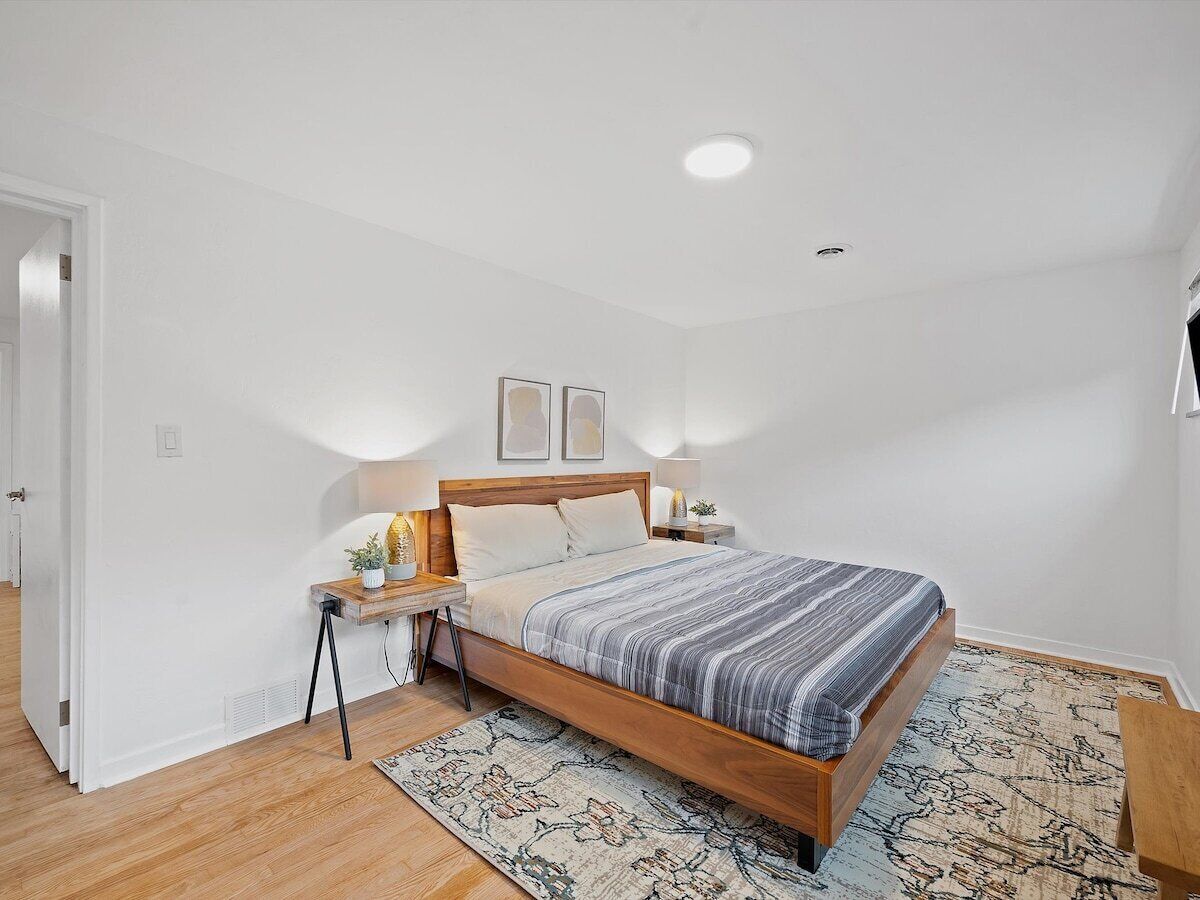 Une chambre à coucher avec un lit en bois, des tables de chevet, une commode et un tapis à motifs.