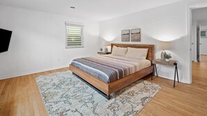 Un dormitorio con una cama de madera, una mesita de noche, una lámpara y una ventana con persianas.