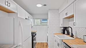 Una cocina moderna con armarios blancos, piso de madera y horno empotrado.