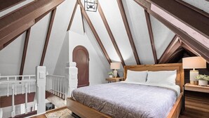 A bedroom with a sloped ceiling, wooden beams, a bed with a headboard, bedside tables, and a nightstand. - Shadyside/Pittsburgh, Modern & Unique 1 Bedroom with Free Parking (Pittsburgh)