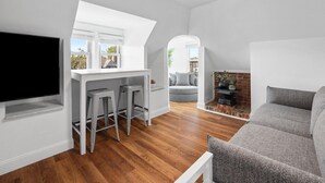 A modern living space with a kitchen area, a seating area with a sofa and chairs, and a fireplace. - Shadyside/Pittsburgh, Modern & Unique 1 Bedroom with Free Parking (Pittsburgh)