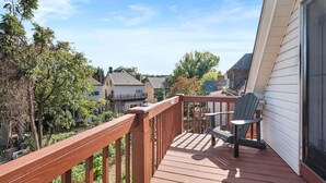 A wooden deck with a railing, two Adirondack chairs, and a view of neighboring houses. - Shadyside/Pittsburgh, Modern & Stylish 1 Bedroom with Free Parking (Pittsburgh)