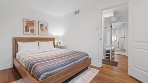 A bedroom with a wooden bed, a nightstand, and a bedside table. There is a door leading to another room. - Shadyside/Pittsburgh, Modern & Stylish 1 Bedroom with Free Parking (Pittsburgh)