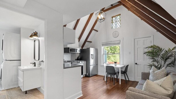 A modern kitchen with white cabinetry, a dining area with a table and chairs, and a cozy seating area with a sofa. - Shadyside/Pittsburgh, Modern & Stylish 1 Bedroom with Free Parking (Pittsburgh)
