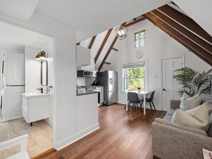 A modern kitchen with white cabinetry, a dining area with a table and chairs, and a cozy seating area with a sofa. - Shadyside/Pittsburgh, Modern & Stylish 1 Bedroom with Free Parking (Pittsburgh)