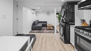 Eine moderne Küche mit Herd, Backofen und Waschmaschine. Ein Essbereich mit Tisch und Stühlen ist ebenfalls vorhanden.