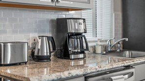 A kitchen with a coffee maker, toaster, and cabinets.