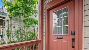 A red door with a window and a '2nd Floor' sign, a mailbox, and a small porch area with a railing. - Shadyside, Central @4 Stylish and Central Studio with Free Parking (Pittsburgh)