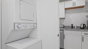 A compact kitchen with white cabinets, a built-in microwave, and a coffee maker on the countertop. - Shadyside, Central @4 Stylish and Central Studio with Free Parking (Pittsburgh)