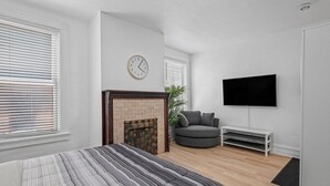 A modern bedroom with a bed, a fireplace, a TV, and a sofa. - Shadyside, Central @4 Stylish and Central Studio with Free Parking (Pittsburgh)