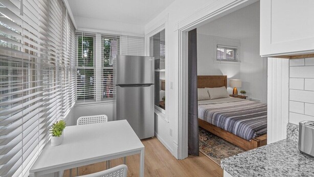 Un studio compact comprenant un coin cuisine, un espace repas, un lit et une petite salle de bain.