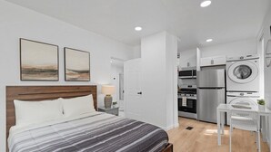 Un dormitorio moderno con una cama grande, una mesita de noche y una pequeña mesa con una silla en una esquina.