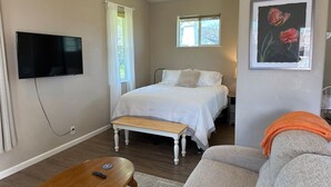 A bedroom with a bed, a TV, a bench, and a sofa. - Stagecoach Cottage quiet efficiency (Middletown)