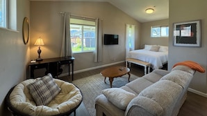 A cozy room with a bed, a sofa, a desk, and a TV. - Stagecoach Cottage quiet efficiency (Middletown)