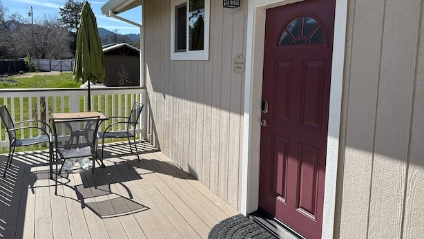 A wooden deck with a red door, a small window, and a sign indicating a 'Guesthouse Cottage'. - Stagecoach Cottage quiet efficiency (Middletown)