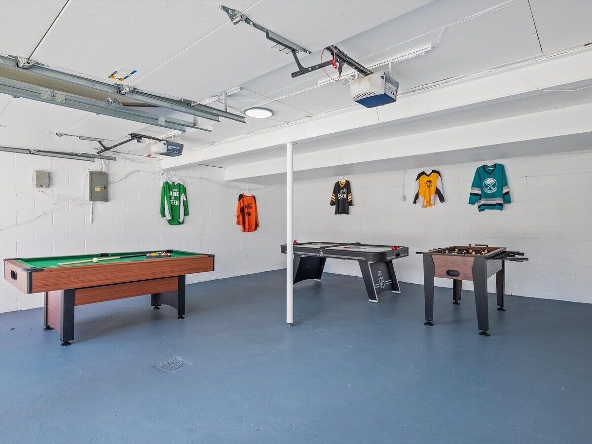 Une pièce équipée d’une table de billard, d’un baby-foot et d’une table de jeu de flipper.