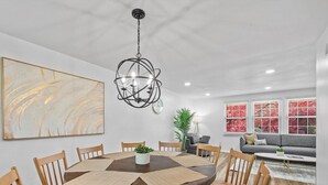 Un comedor con una mesa redonda, sillas de madera, una planta en el centro y una lámpara moderna.