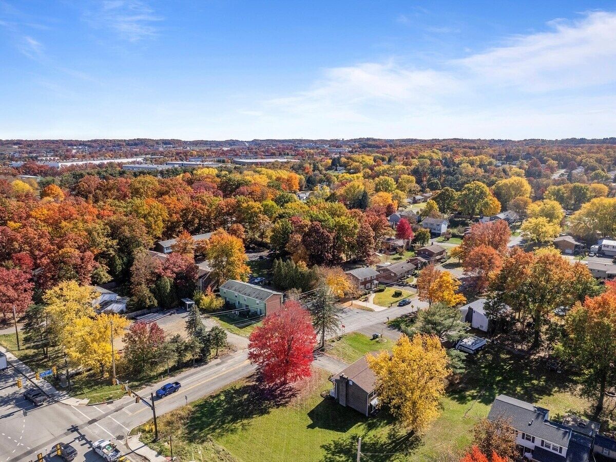 An aerial view of a residential area with houses surrounded by autumn-colored trees.