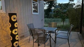 An outdoor patio with a table and chairs, a tall decorative light post, and a view of a house and trees. - Emerald Lodge quiet efficiency (Middletown)