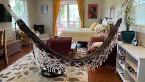 A cozy living room with a hammock, a bed, and a TV.
