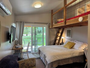 A bedroom with a bed, a desk, a chair, a TV, a window, and a balcony. - Love Shack private retreat (Middletown)