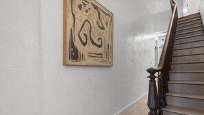 Eine Treppe mit einem Holzgeländer und einer beigen Wand mit einem gerahmten abstrakten Gemälde.