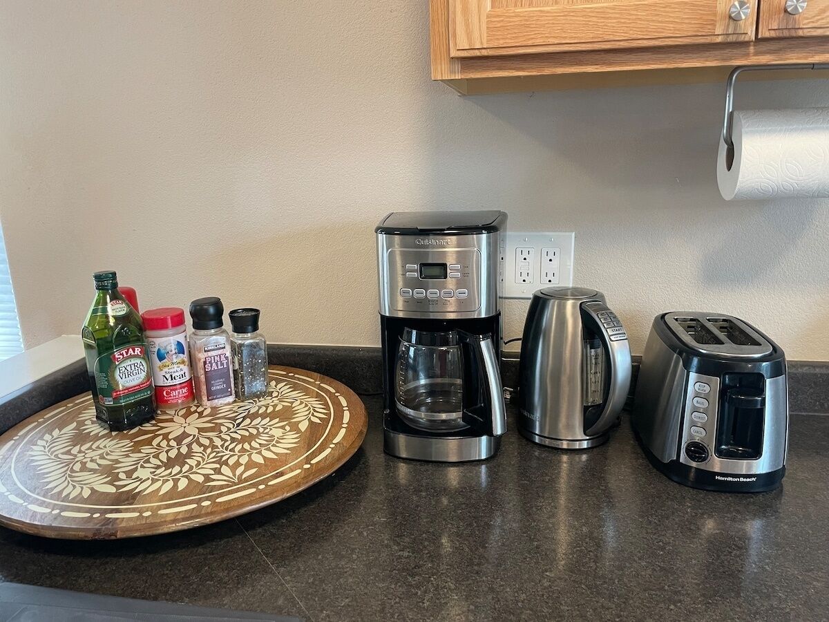 A kitchen counter with a coffee maker, toaster, and a decorative tray with condiments.