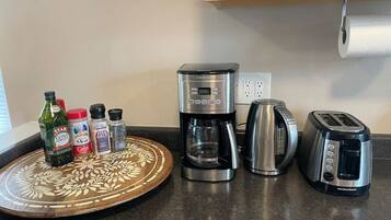 A kitchen counter with a coffee maker, toaster, and a decorative tray with condiments.