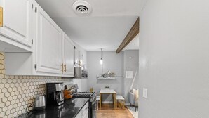 Una cocina compacta con armarios blancos, encimera negra y suelo de madera.