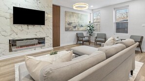 Een moderne woonkamer met een flatscreen televisie, een open haard en een grote bank.