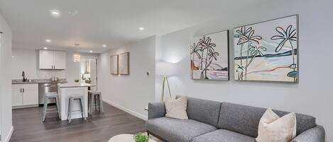 A modern living room with a grey sofa, a coffee table with a plant, and artwork on the wall.