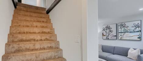 A staircase with carpeted steps leading to a landing.