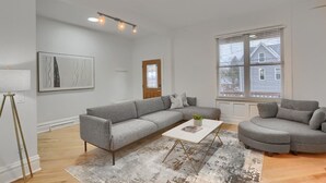 A modern living room with a grey sectional sofa, a white coffee table, and a patterned rug. - Modern & Spacious 4BD House in Pittsburgh with Free Street Parking (Pittsburgh)