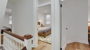 A bedroom with a bed, nightstand, lamp, and a window with blinds. - Modern & Spacious 4BD House in Pittsburgh with Free Street Parking (Pittsburgh)