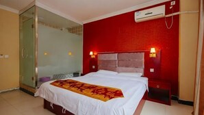 Habitación de hotel con cama, cabina de ducha de vidrio, pared roja y aire acondicionado mural.