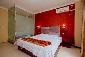 Une chambre d’hôtel avec un lit, une douche en verre, un mur rouge et un climatiseur fixé au mur.