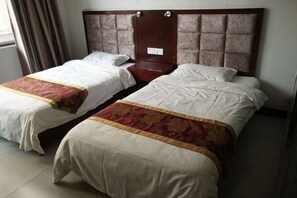 Dos camas individuales con cabeceras, una mesita de noche de madera y una ventana con cortinas.
