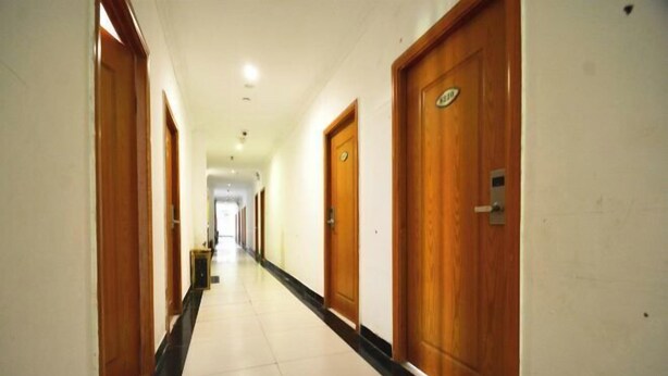 Un largo y estrecho pasillo de hotel con puertas de madera a ambos lados y suelo de baldosas.