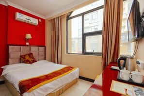 A hotel room with a bed, a desk with a kettle, a television, and an air conditioning unit. - Zhongguo Maidi Express Hotel (Zhongmu)