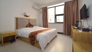 Una habitación de hotel con cama, mesita de noche, televisión y ventana con cortinas.