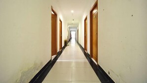Un pasillo largo y estrecho con puertas de madera a ambos lados, que conduce a una habitación luminosa al final.