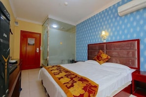 Una habitación de hotel con una cama, una mesita de noche roja, una ducha con cerramiento de vidrio y una puerta roja.
