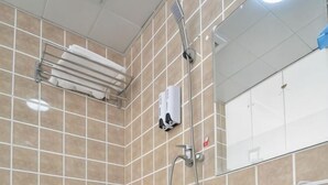 Zona de ducha con azulejos, un perchero, un cabezal de ducha manual y un dispensador de jabón.