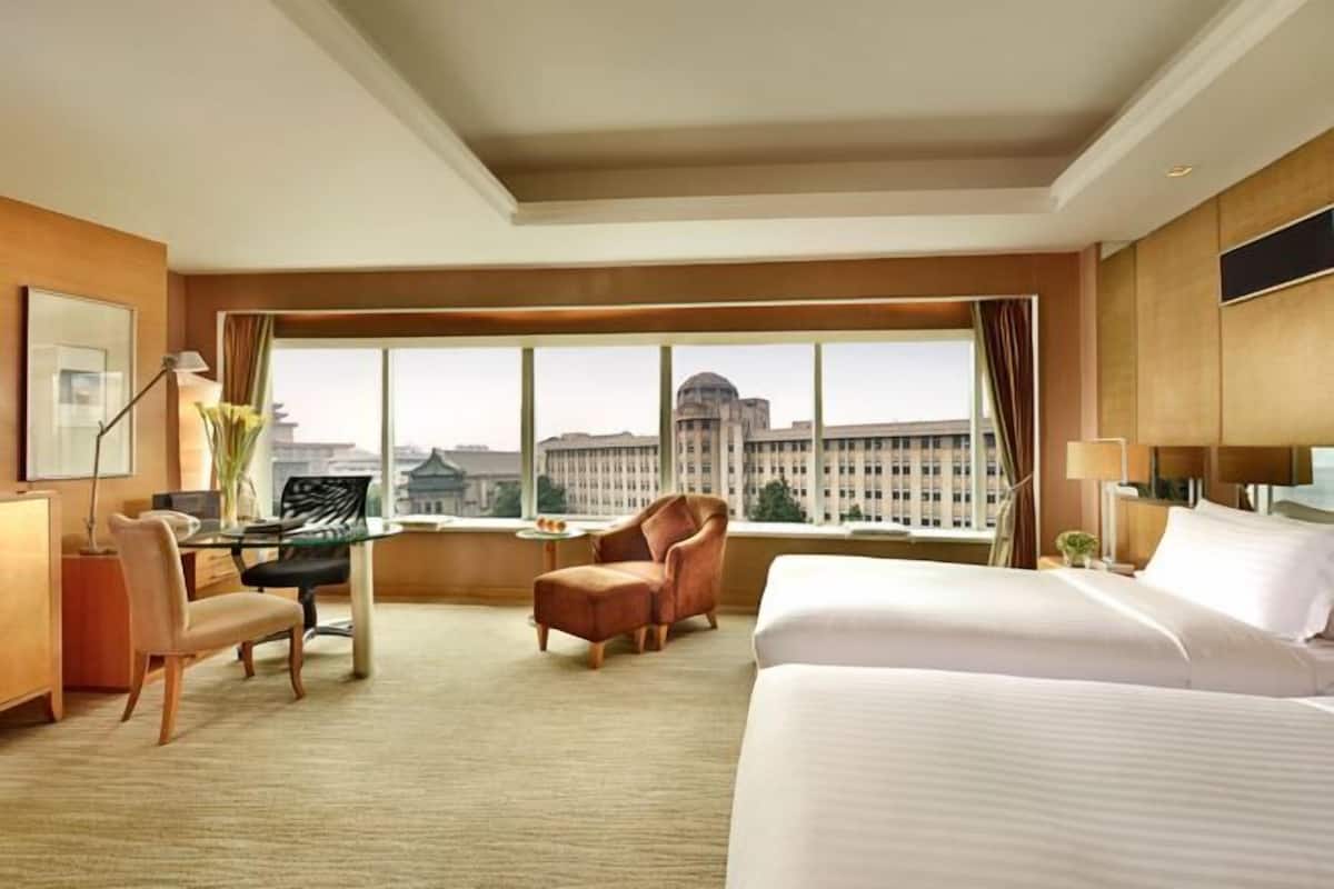 Une chambre d’hôtel avec un grand lit, un bureau, une chaise et une vue sur le paysage urbain.
