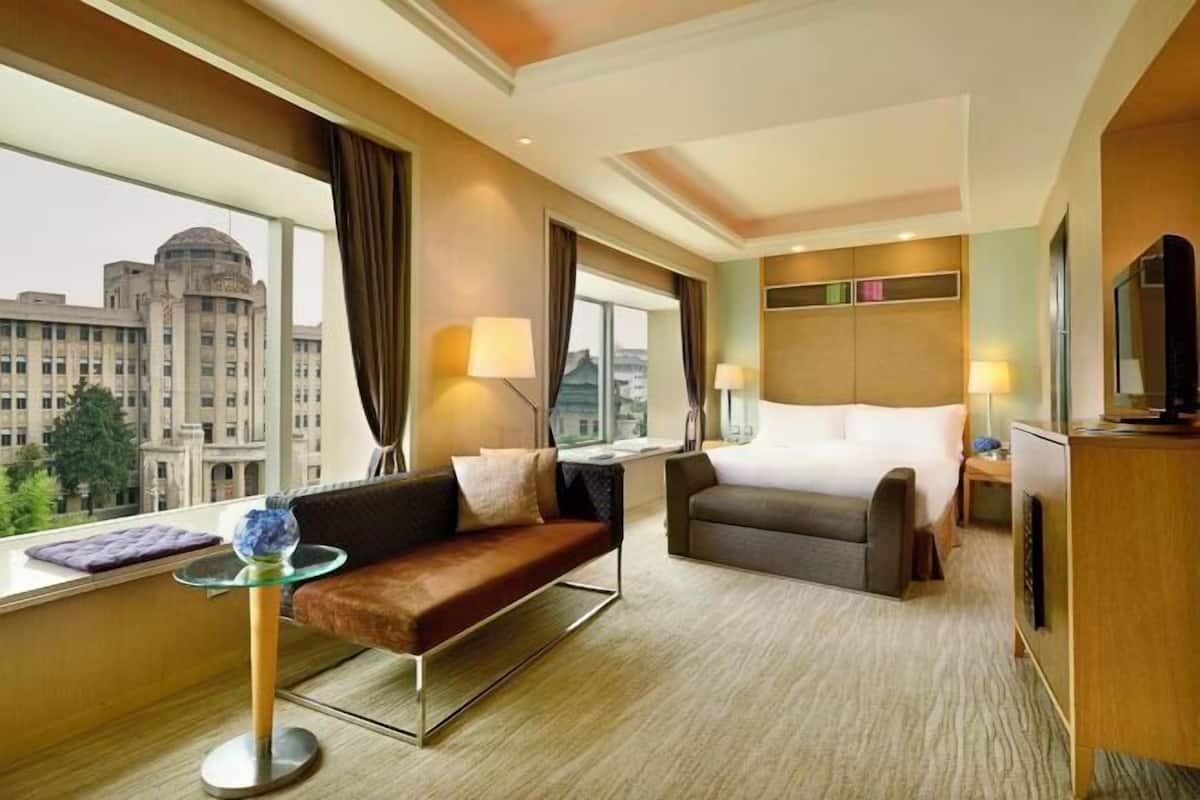 Une chambre d’hôtel avec un lit, un canapé, une petite table et un téléviseur.
