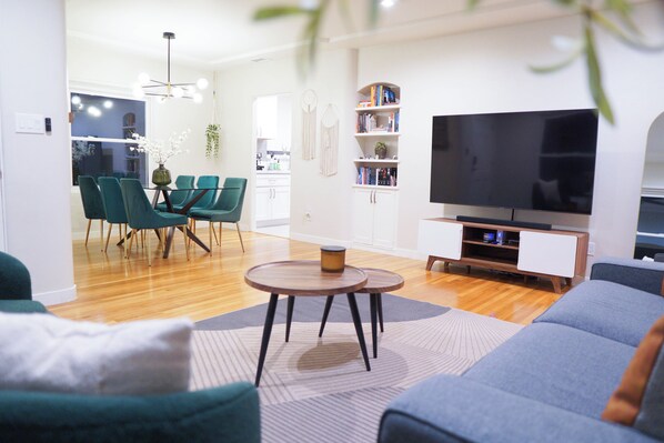 A modern living room with a sofa, chairs, a coffee table, a TV, and a bookshelf.