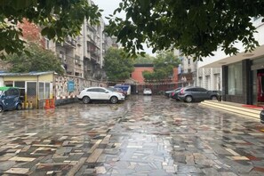 A parking area with cars, a small kiosk, and buildings in the background. - Jingyi Boutique Hotel (Anqing Petrochemical No.1 Middle School) (Anqing)