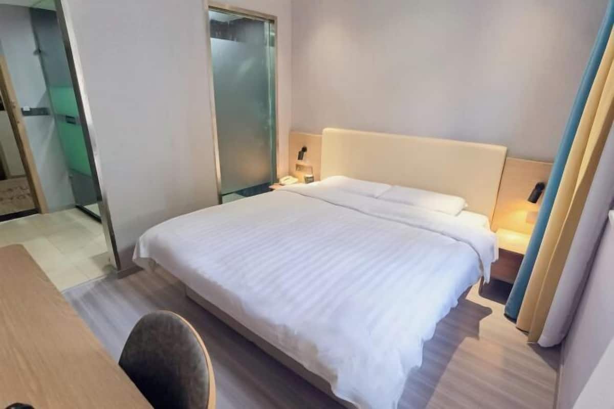 A hotel room with a large bed, bedside tables, a desk, and a chair.