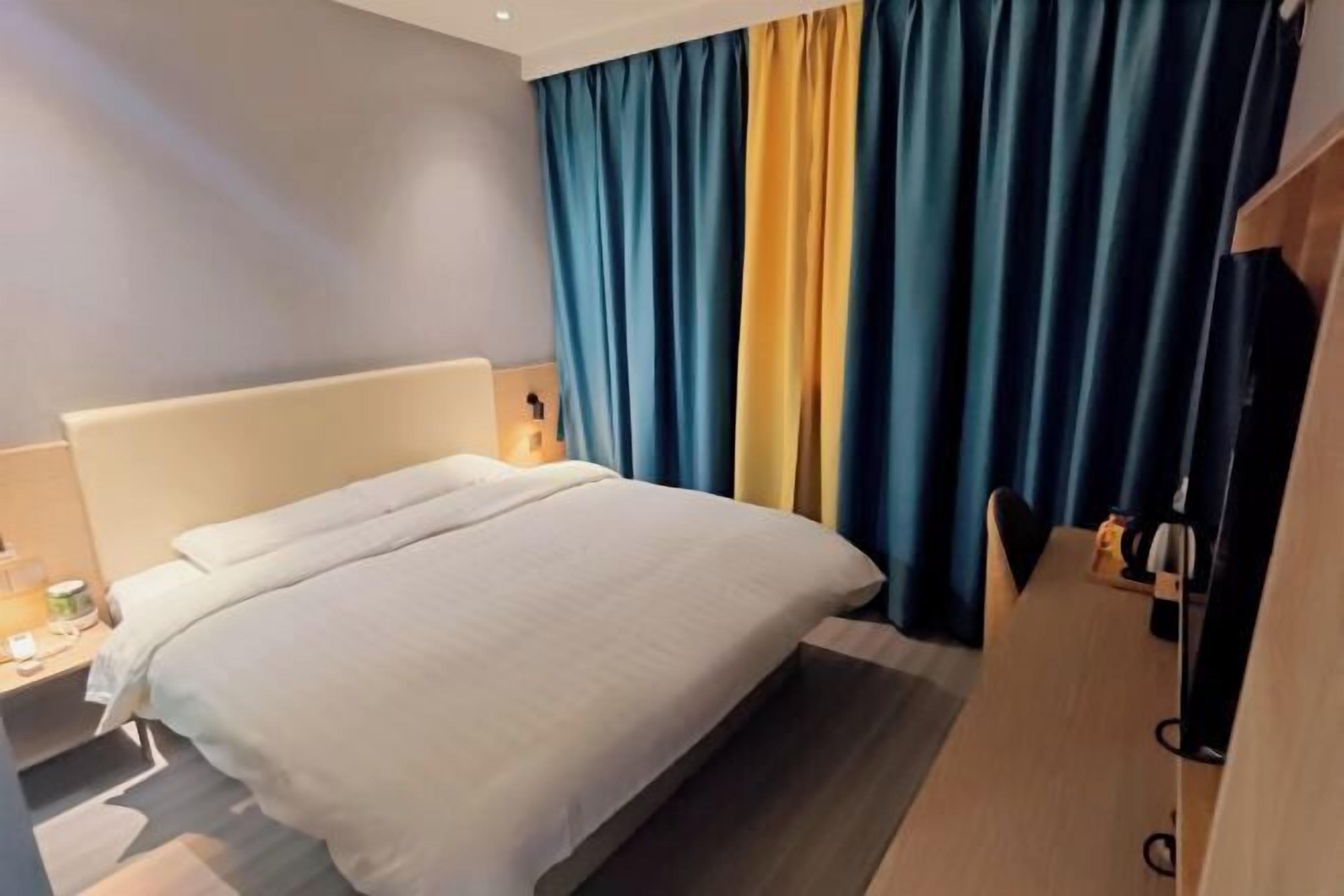 Una habitación de hotel con una cama, un escritorio, una lámpara y un televisor.