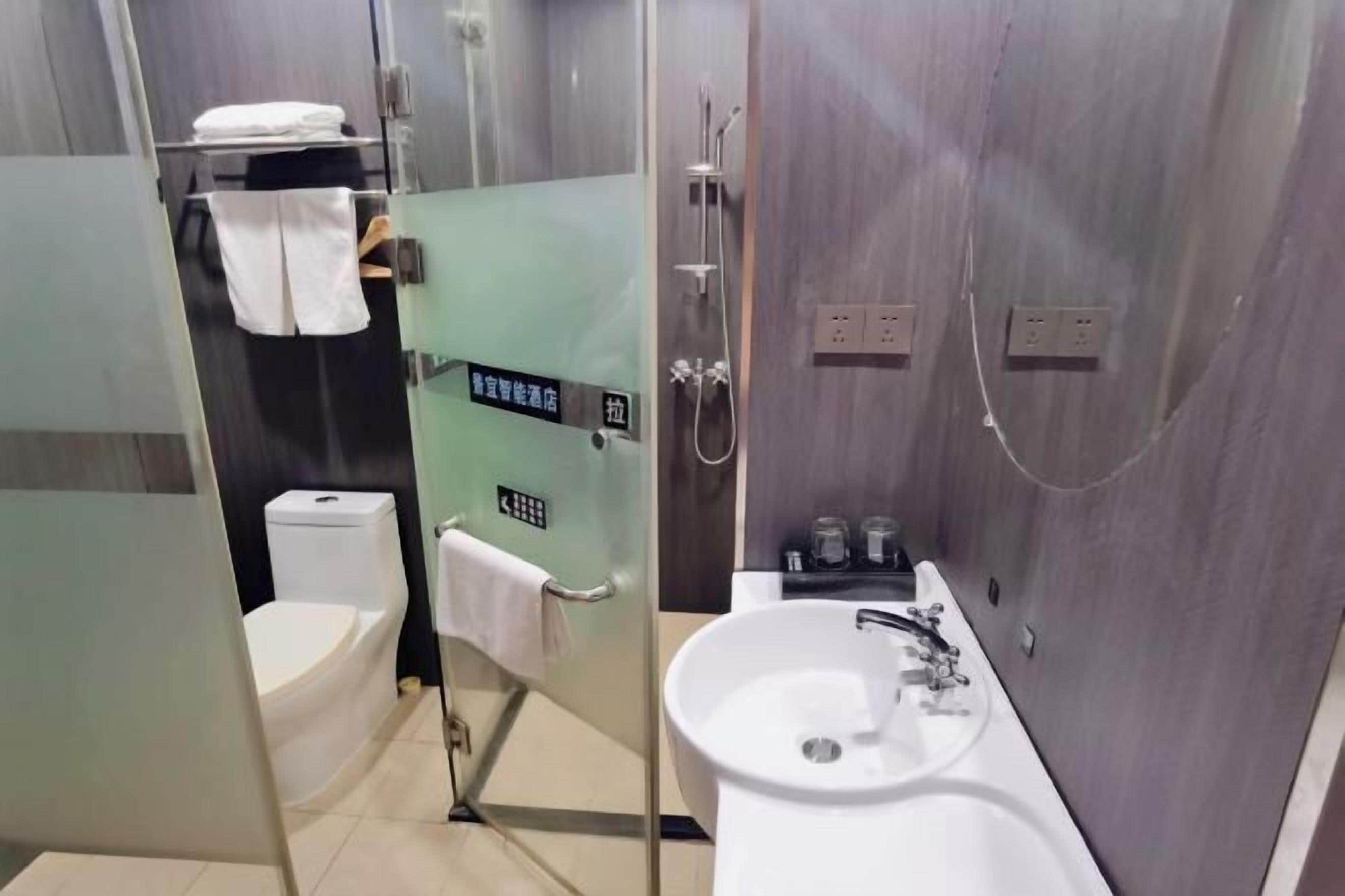 A modern bathroom with a glass-enclosed shower, a white sink, and a toilet.